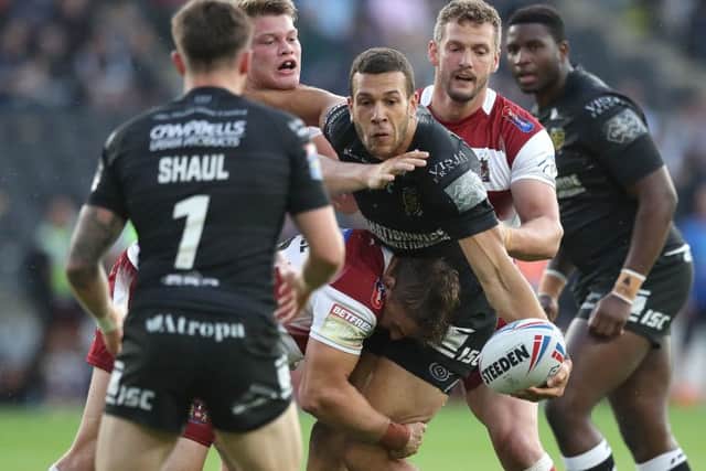 Hull FC's Carlos Tuimavave is tackled by Wigan Warriors Morgan Smithies (left), Sam Powell and Sean O'Loughlin (right).