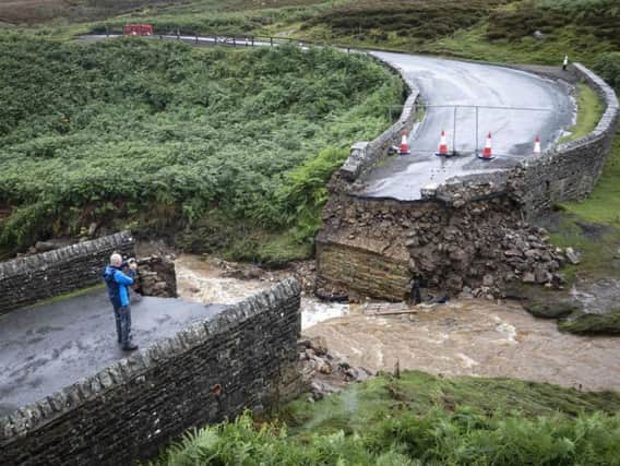 A man takes a photograph of a collapsed bridge near Grinton, North Yorkshire, after "unprecedented" flooding in the Yorkshire Dales. Picture by Danny Lawson/PA Wire.