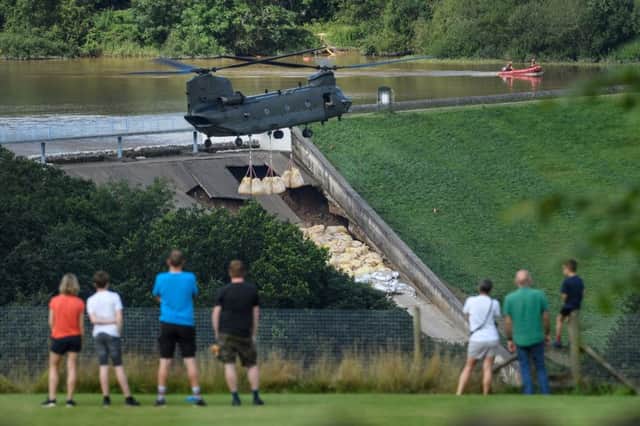 Residents look on as an RAF Chinook helicopter drops sandbags onto the dam wall at Toddbrook reservoir following a severe structural failure after heavy rain, on August 02, 2019 in Whaley Bridge. (Photo by Leon Neal/Getty Images)