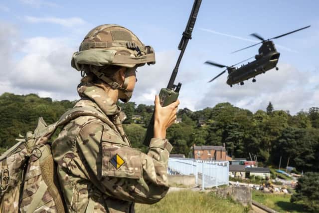 Handout photo issued by the Ministry of Defence (MoD) of personnel on the ground and an RAF Chinook Mk6a helicopter as it approaches the Toddbrook Reservoir dam near the village of Whaley Bridge.