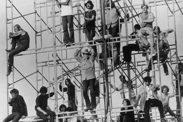 Music fans climbing the sound tower to secure a better viewing point at Woodstock in 1969.