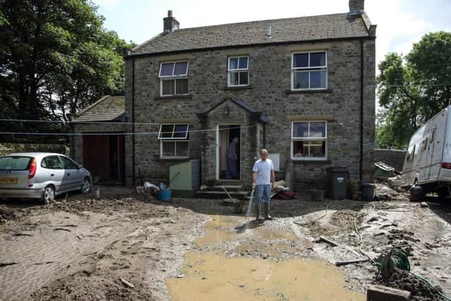A man surveys the remains of his front garden in Reeth after flash floods destroyed it