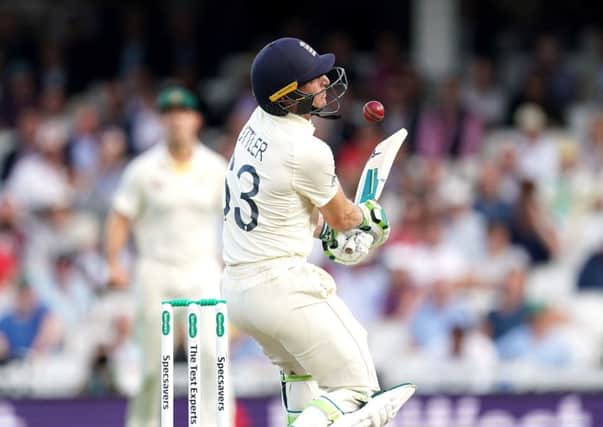 England's Jos Buttler is hit in the face by the ball.