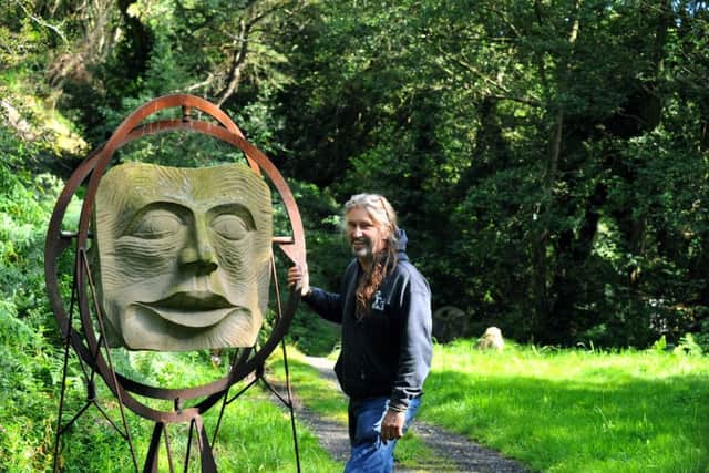 Andrew Vickers  of Stoneface Creative , with his  'Behind the Mask'  sculpture in the woods at Storrs  in South Yorkshire .