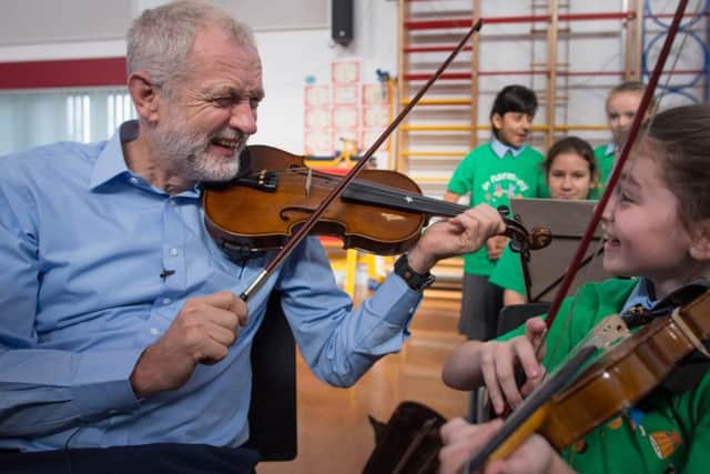 Labour leader Jeremy Corbyn is given a violin lesson by 10 year old Jessica Kelly during a visit to Faith Primary School in Liverpool, where he met children taking part in the In Harmony project, which is supported by the Royal Liverpool Philharmonic  Orchestra and is helping school children learn to play musical instruments.