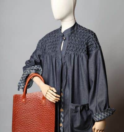 The Honeycomb features a flattering, fluid silhouette, with intricate honeycomb smocking which gently wraps over to the back of the dress, contrast Japanese fabric on inner cuff and collar, 
inverted back pleat, deep gently gathered pockets with twin stitch detail, underarm godets for extra fullness and gently gathered cuff, £650. Bag by JS-Y Leatherworks.