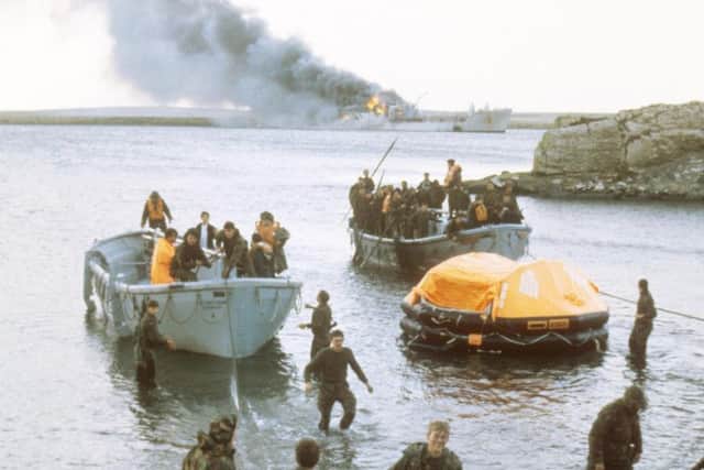 File photo dated 08/06/1982 of survivors of the attack on RFA Sir Galahad coming ashore in life rafts at San Carlos Bay as the supply ship blazes in the background. PRESS ASSOCIATION Photo.Martin Cleaver/PA Wire
