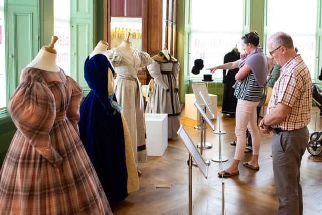 Visitors examine costumes from Gentleman Jack