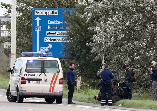 Police officers detain a group of men thought to be migrants near the port of Zeebrugge in Belgium after 39 bodies were found inside a lorry that had travelled from the port to the Port of Tilbury in Essex.