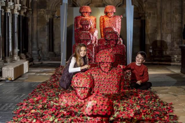 Brother and sister William, 7 and Ruby Morris, 9 at the Martin Water's War memorial art installation at Beverley Minster in Beverley, East Yorkshire. The poppy installation is created in rememberance of all those who died in the Battle of Normandy, France in 1944 and the fate that awaited them as they disembarked the landing craft. Credit: Dan Rowlands / SWNS.com