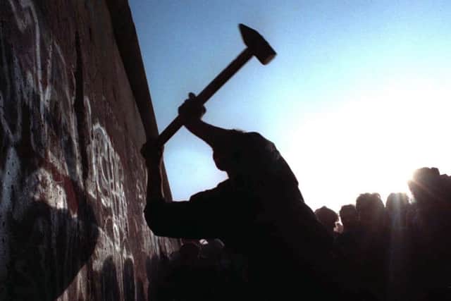 A man hammers away at the wall thirty years ago. (AP).