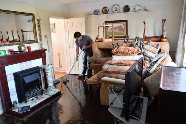 Paul Croucher mops his parents' living room after it was flooded in Fishlake, Doncaster as parts of England endured a month's worth of rain in 24 hours, with scores of people rescued or forced to evacuate their homes. Ben Birchall/PA Wire
