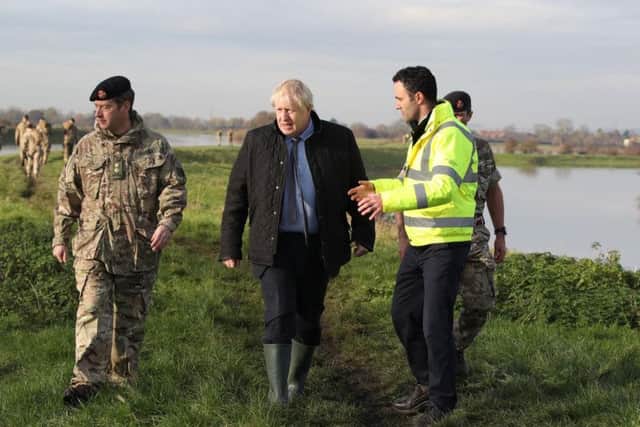 Prime Minister Boris Johnson walks with Lt Col Tom Robinson from the Light Dragoons and Oliver Harmar, Yorkshire Area Director of the Environment Agency, during a visit to Stainforth, Doncaster, to see the recent flooding. Pic: PA