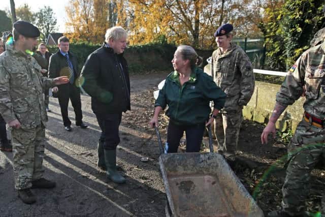 Prime Minister Boris Johnson talks with a local woman pushing a wheelbarrow during a visit to Stainforth, Doncaster, to see the recent flooding. Pic: PA