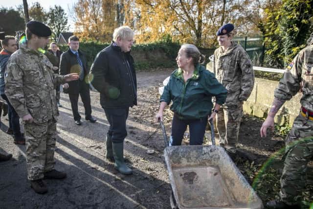 Prime Minister Boris Johnson talks with a local woman pushing a wheelbarrow during a visit to Stainforth, Doncaster, to see the recent flooding. Photo: Danny Lawson/PA Wire