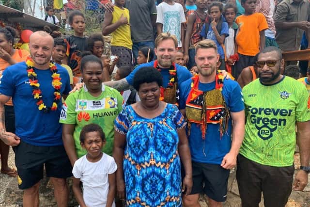 Great Britain's Josh Hodgson, left, Blake Austin, middle, and Elliott Whitehead visit the grave of former Canberra Raiders team-mate Kato Ottio in his home village in Papua New Guinea. (CREDIT: RFL)