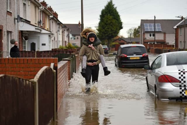 People wade through floodwater as they pass houses on a flooded street in Doncaster.
