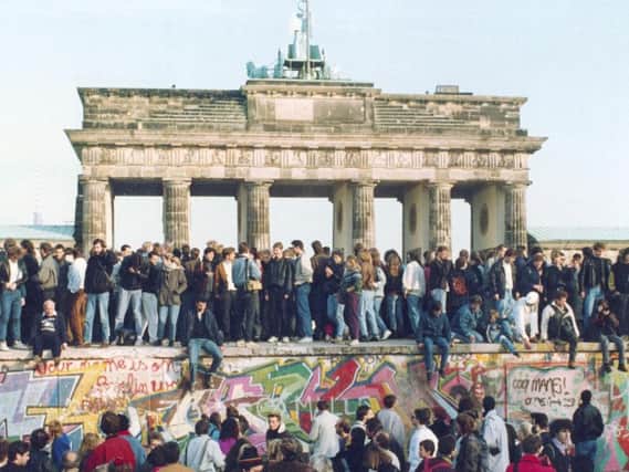 November 1989, East and West Germans stand on the Berlin Wall.