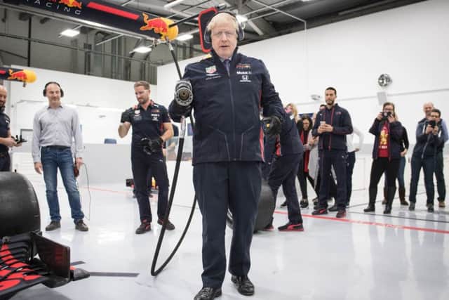 Prime Minister Boris Johnson attempts to change a wheel of a Formula One car during a visit at Red Bull Racing while election campaigning in Milton Keynes.