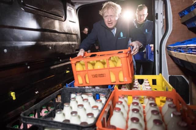 Boris Johnson loads milk and orange juice into a delivery truck in Yeadon. Photo: PA