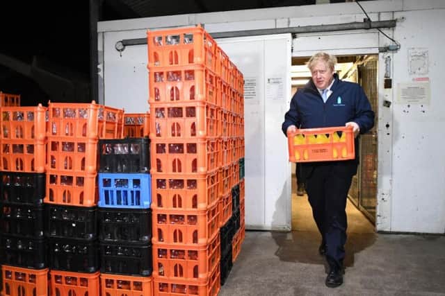 Prime Minister Boris Johnson carries a crate during a visit to Greenside Farm Business Park. Photo: Stefan Rousseau/PA Wire