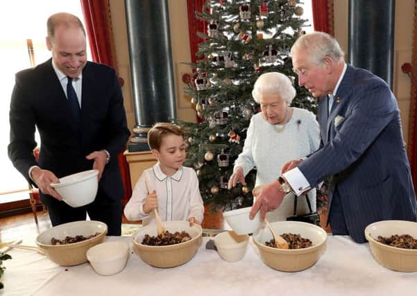 Queen Elizabeth II, the Prince of Wales, the Duke of Cambridge and Prince George preparing special Christmas puddings in the Music Room at Buckingham Palace, London, as part of a Royal British Legion project.