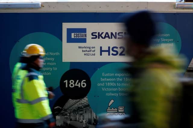 Workers stand near a sign outide a construction site for a section of Britain's HS2 high-speed railway project, at London Euston train station in London on January 20, 2020. -(Photo by Tolga AKMEN / AFP)