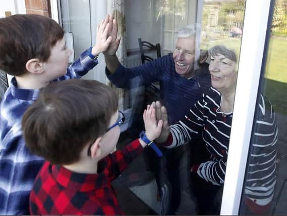 Ben and Isaac talk to their grandparents Sue and Alan through a window, as they self-isolate at their home in Knutsford, Cheshire. Picture: Martin Rickett/PA Wire
