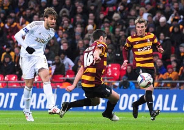 Swansea City's Miguel Michu (left) scores their second goal of the game during the Capital One Cup Final match at Wembley Stadium as Bradford fans look on in despair.