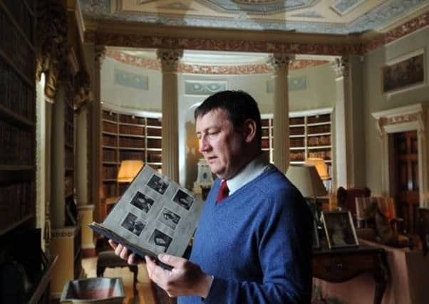 Stuart Gill in the library at Newby hall with old photograph album with images from WWII at Newby Hall.