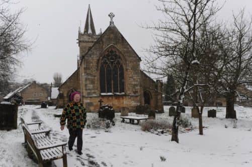 A woman makes her way through the snow covered All Saints Churchyard in Bramham, West Yorkshire.