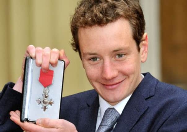 Alistair Brownlee holds his MBE after the Investiture Ceremony in Buckingham Palace