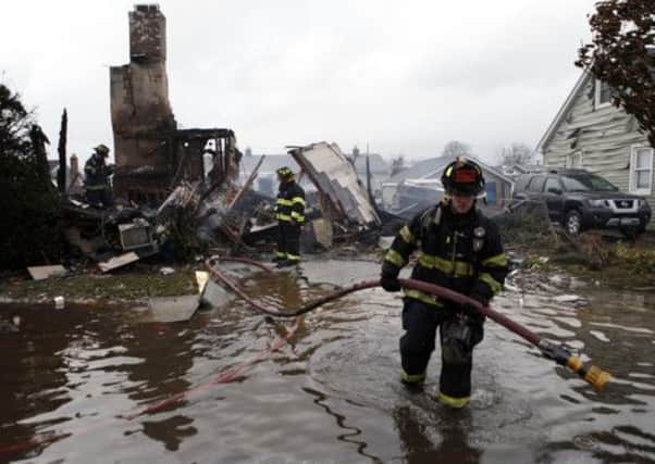 Firefighters work at the scene of a house fire in the aftermath of superstorm Sandy