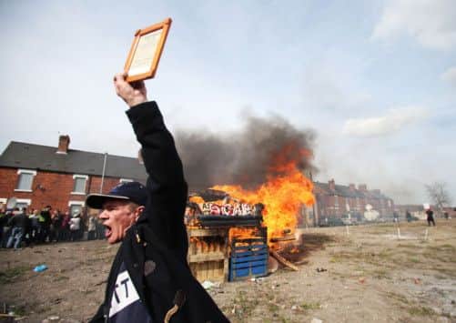 A miner in Goldthorpe, Yorkshire cheers as protesters set fire to a coffin containing an effigy of Margaret Thatcher after a protest march.