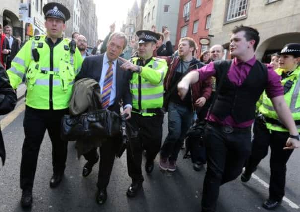 UKIP leader Nigel Farage being escorted by police officers as he leaves the Cannons Gait pub as protestors heckle him
