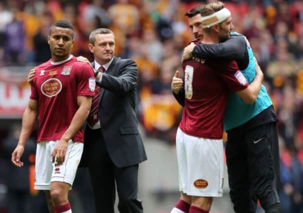 Northampton Town manager Aidy Boothroyd consoles his players.