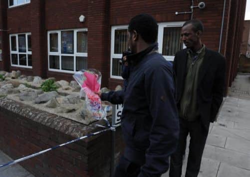 Men lay a floral tribute close to the scene where a man was murdered in John Wilson Street, Woolwich.