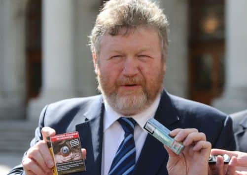 Irish Health Minister James Reilly holds examples of plain pack cigarettes