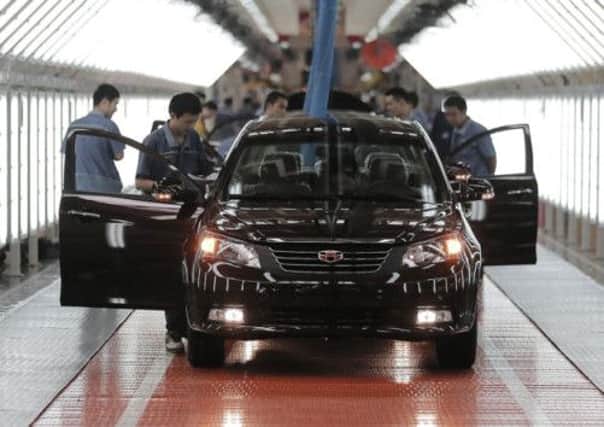 Workers check a car at Chinese automaker Geely Cixi Manufacture Base in Cixi. China