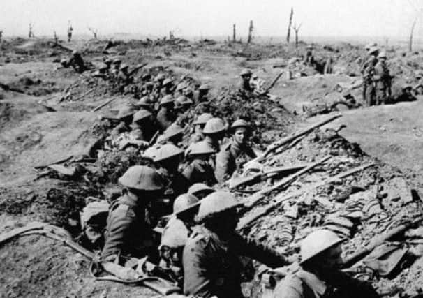 British infantrymen occupying a shallow trench in a ruined landscape before an advance during the Battle of the Somme.