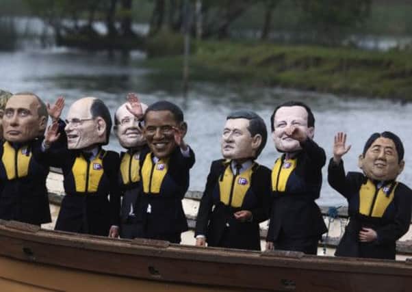 Anti-hunger activists, wearing giant head masks depicting the G-8 leaders, sail on a boat past the hotel where the G8 summit media center is located in Enniskillen, Northern Ireland