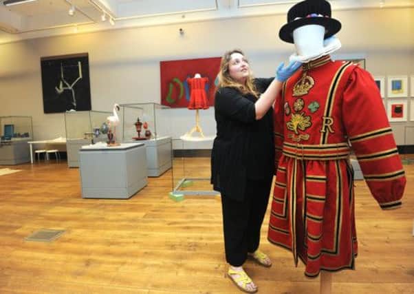 Exhibitions and Displays manager Kirstie Hamilton installing a vibrant red Beefeater costume which belonged to Sheffield born Chief Yeoman of the Guard (1967-70) ,Cyril Taylor.
