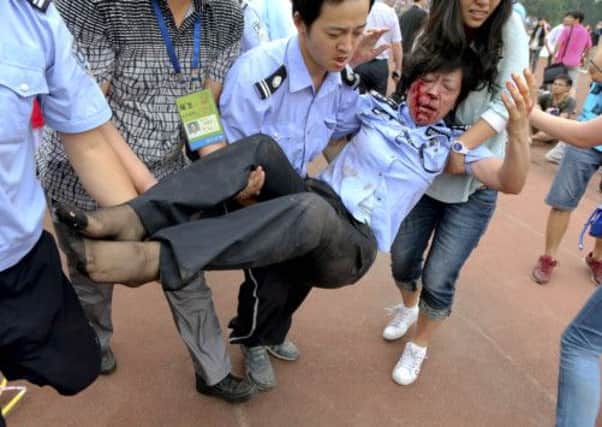 A security officer and others attempt to carry a  policewoman injured in a stampede by fans of David Beckham at a university in Shanghai