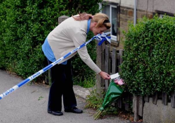 A neighbour lays flowers at the murder scene, Prospect Grove, Shipley.