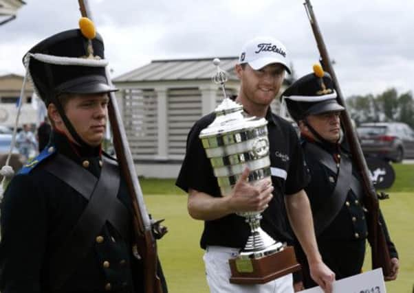 Northern Ireland's Michael Hoey, centre, holds his trophy as two carabineers escorted him off the course,  after the winning in the final round at the Russian Open golf tournament at Tseleevo Golf and Polo Club outside in Moscow, Russia. (AP Photo/Alexander Zemlianichenko)