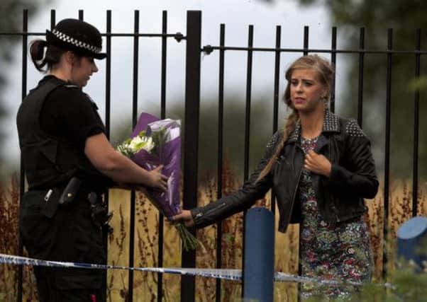 A well-wisher hands over some flowers to a police officer at the scene of a stabbing in Moston, Manchester.