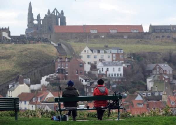 Walkers enjoy the view of Whitby Harbour and St Marys Church from the West Cliff