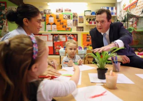 George Osborne plays with Titas (centre) and Taylor (left), during a visit to a nursery in Hammersmith, London.