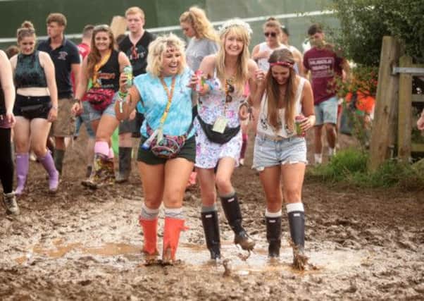 Rebecca Henderson, 20, Annmarie Shannon, 22, and Helen Welburne, 22, walking through the mud at Leeds Festival. PIC: Ross Parry