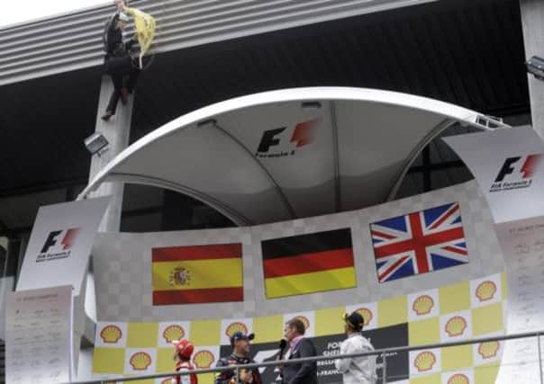 A Greenpeace activists stages a protest during the podium celebration after the Belgium Formula One Grand Prix at the Spa-Francorchamps circuit, Belgium, Sunday, Aug. 25, 2013. (AP Photo/Luca Bruno)